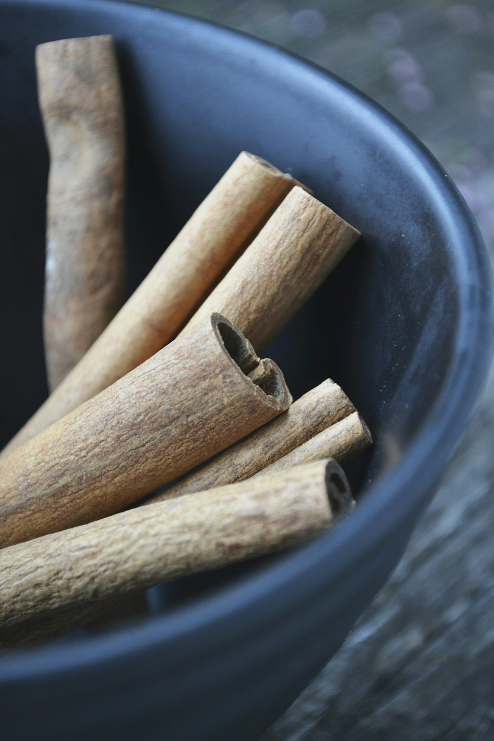 A gift box of cinnamon sticks and whole spices in dark ceramic bowls
